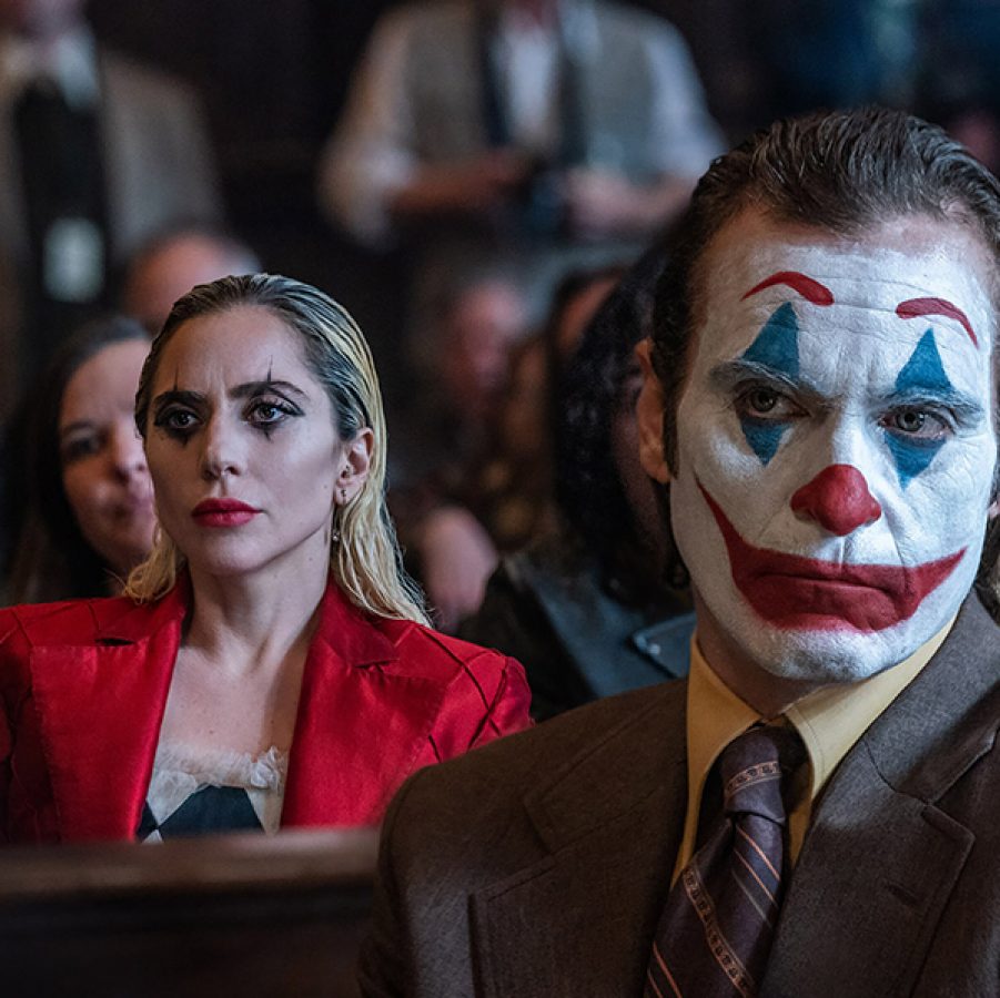 From left, Lee Quinzel (Lady Gaga) and Arthur Fleck (Joaquin Phoenix) wear clown face paint while sitting in a courtroom, in a scene from Joker: Folie à Deux.